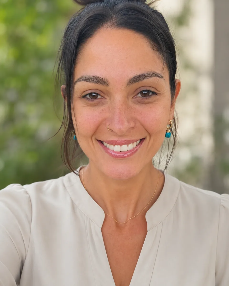 Juliana Sanches smiling, with her hair tied back and wearing a light blouse